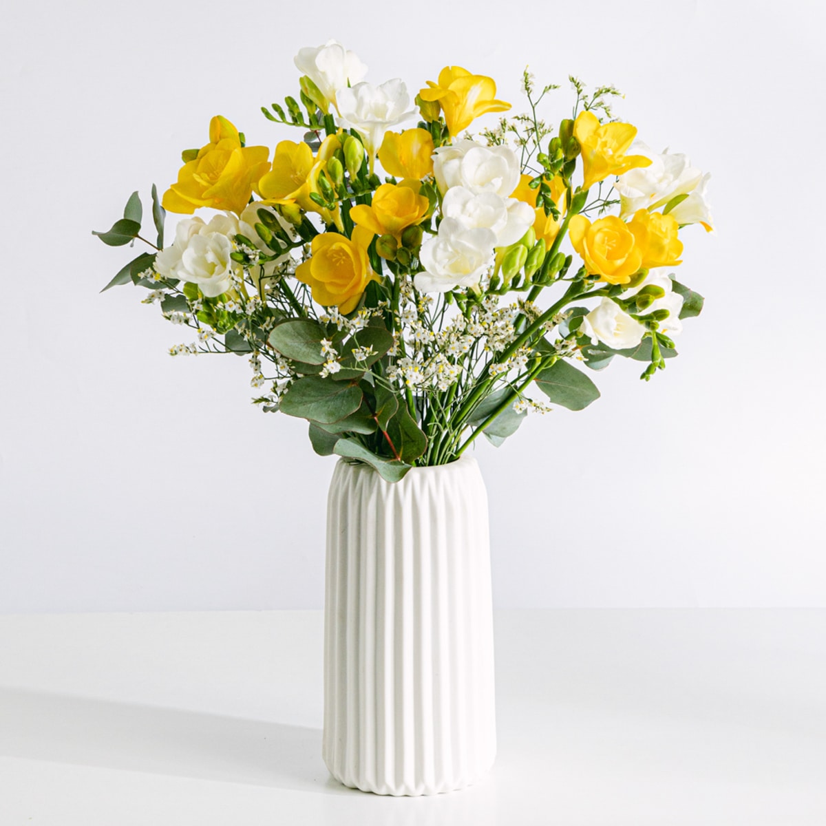 Blumenstrauß aus gelben und weißen Freesien mit Vase