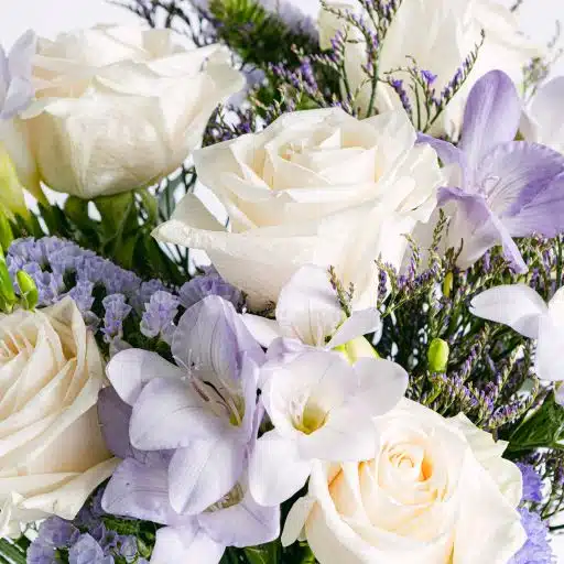 Detail einer Blüte weißer Rosen mit Freesien und Limonium