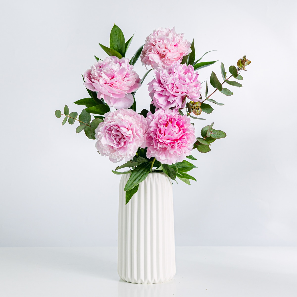 Blumenstrauß aus rosa Pfingstrosen in einer weißen Vase